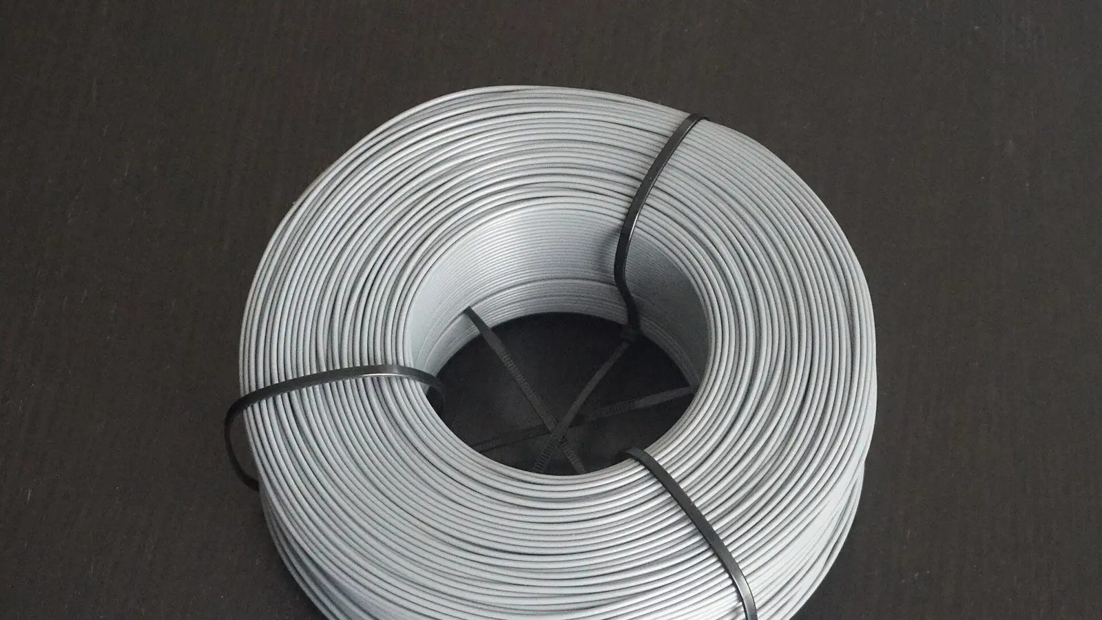 Spool of white printing filament staged beside a printer