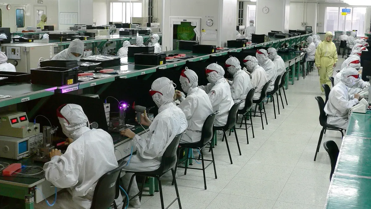 Operators in bunny suits working at cleanroom assembly benches